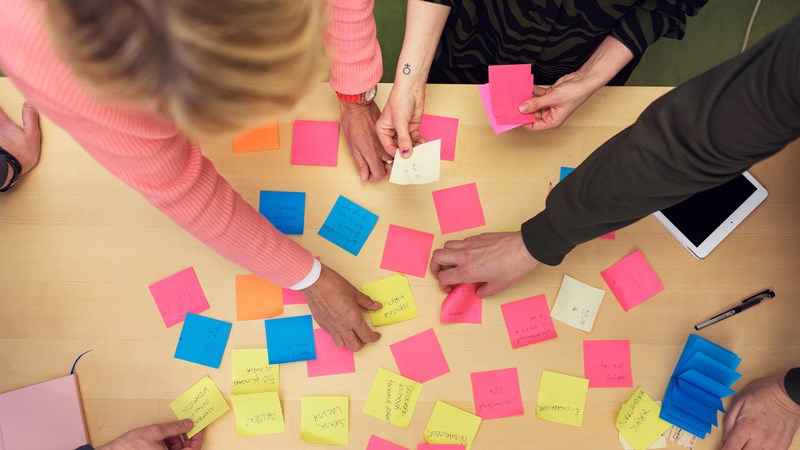 Händer runt post-it-lappar med anteckningar.